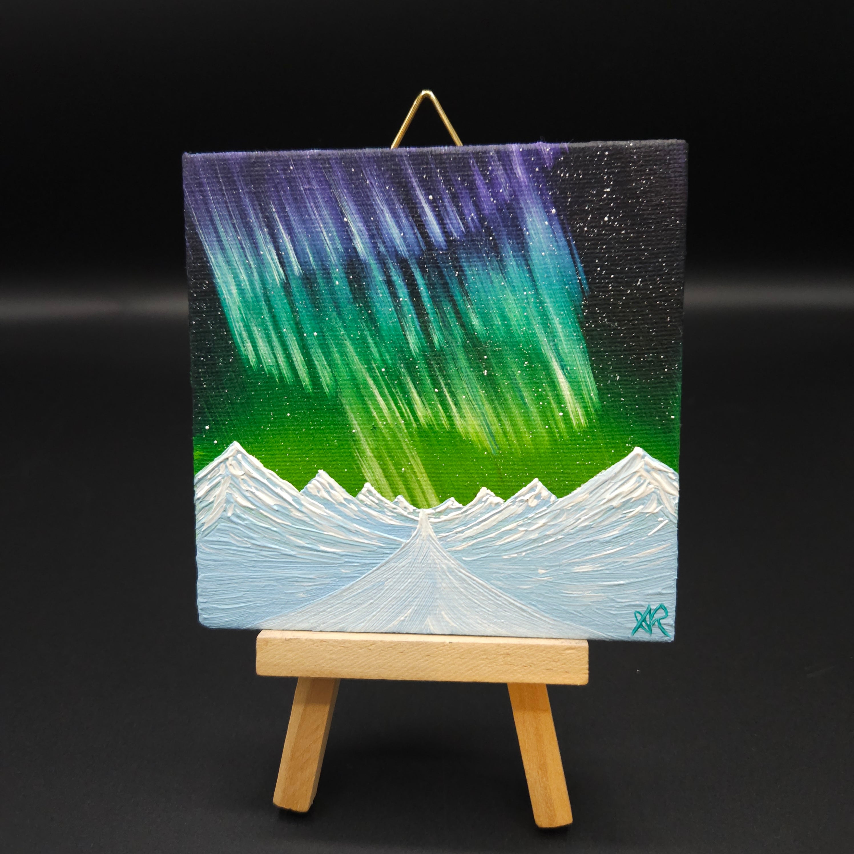 Northern lights landscape painting featuring purple and green northern lights over snow-capped mountains.