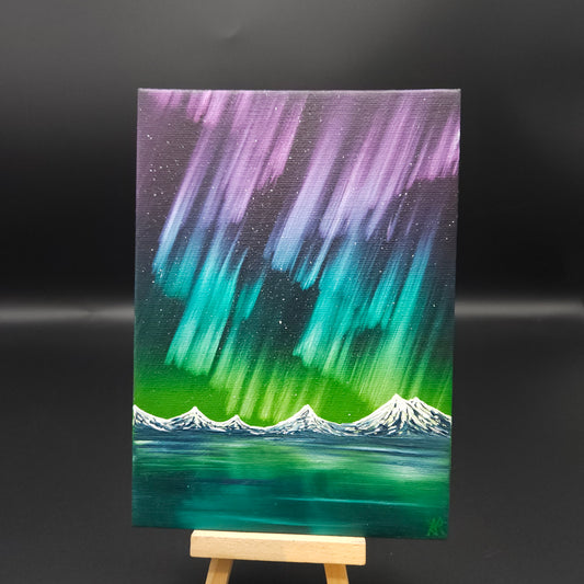 Northern lights landscape painting featuring pink, blue and green northern lights over snow-capped mountains reflected in water.