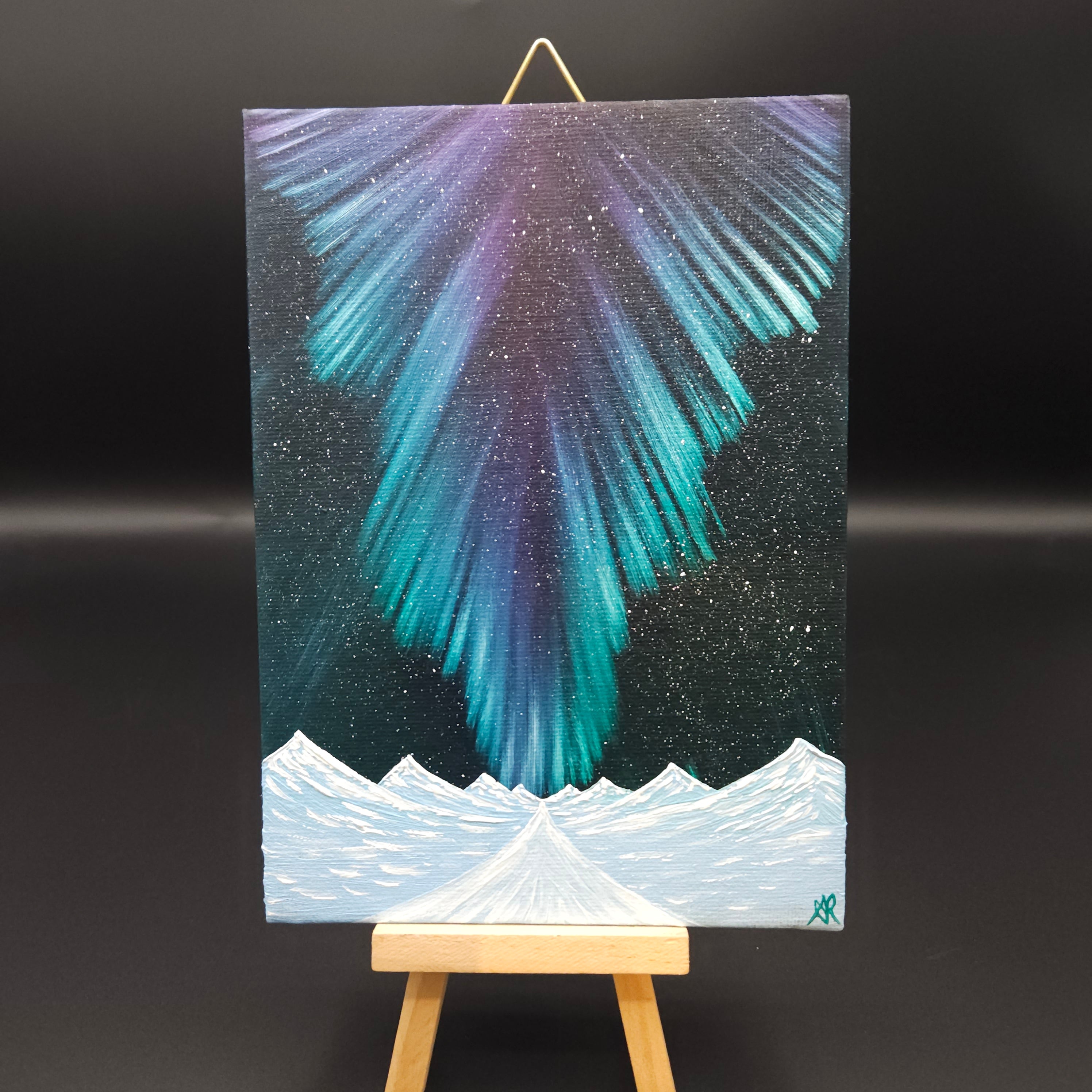 Northern lights landscape painting featuring blue and purple northern lights over a snow-capped mountains.