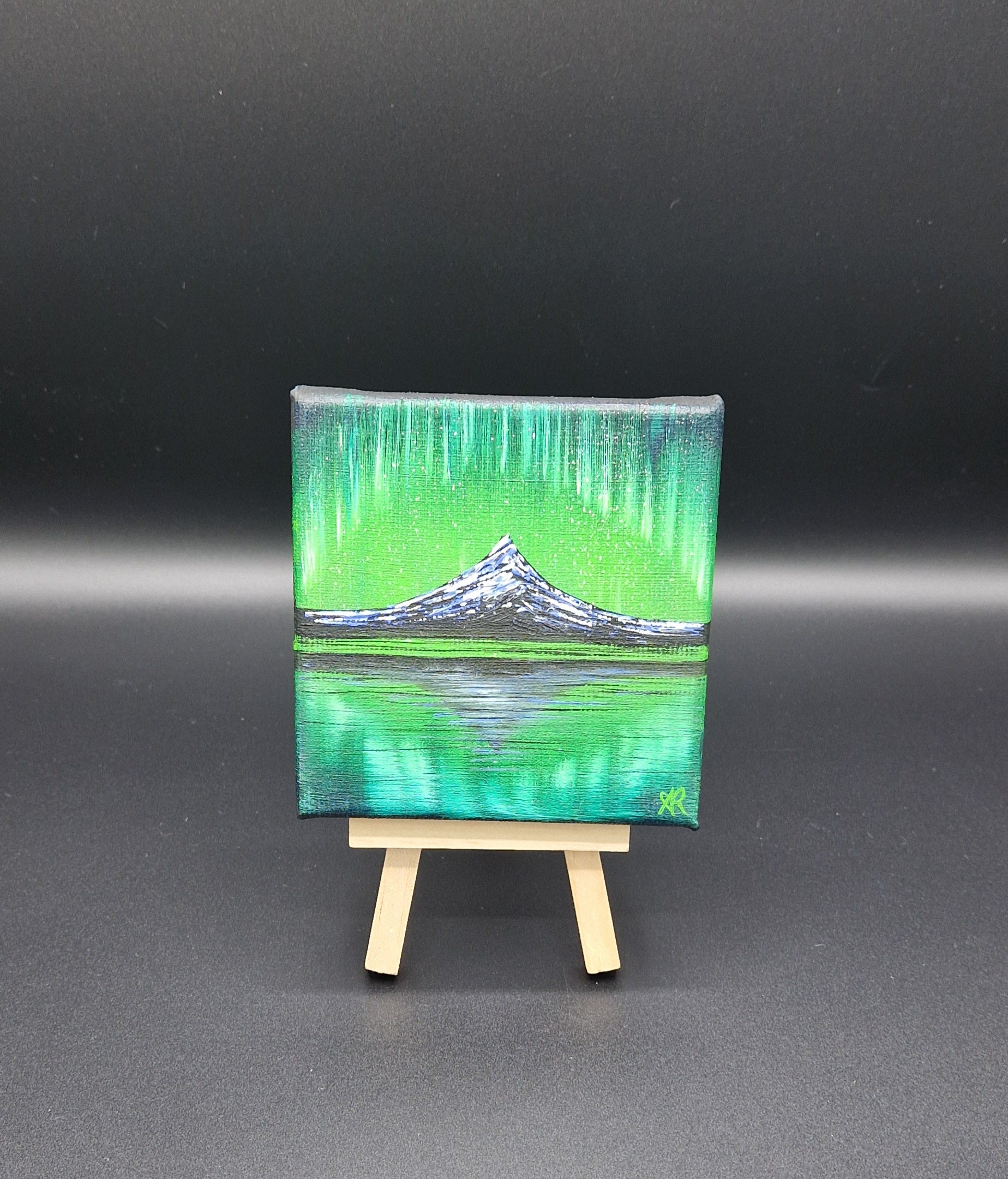Small painting of a mountain landscape with northern lights on a black background