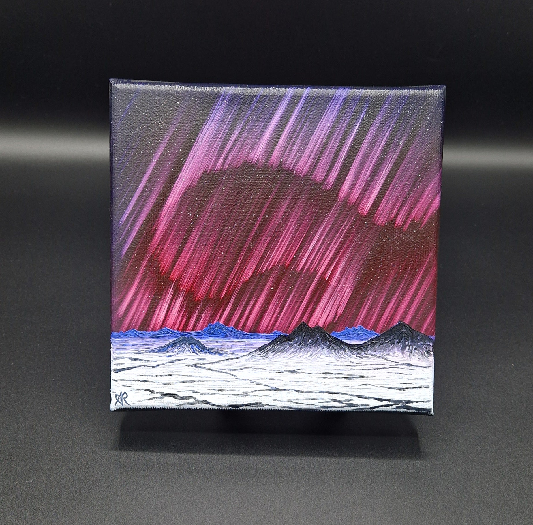 Canvas print of a mountain landscape with pink and purple northern lights on a black background