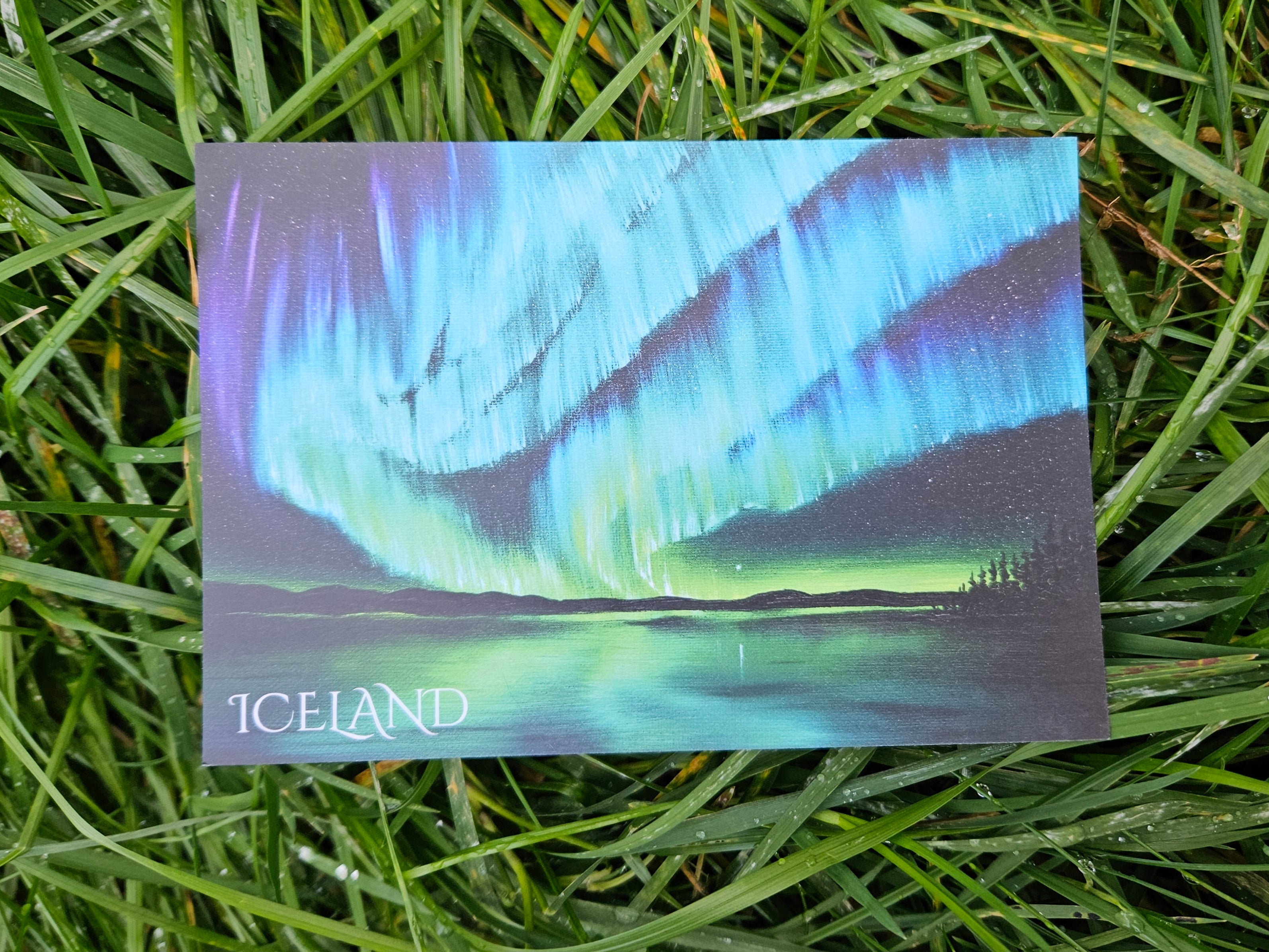 Postcard of the Northern Lights in Iceland lying on grass