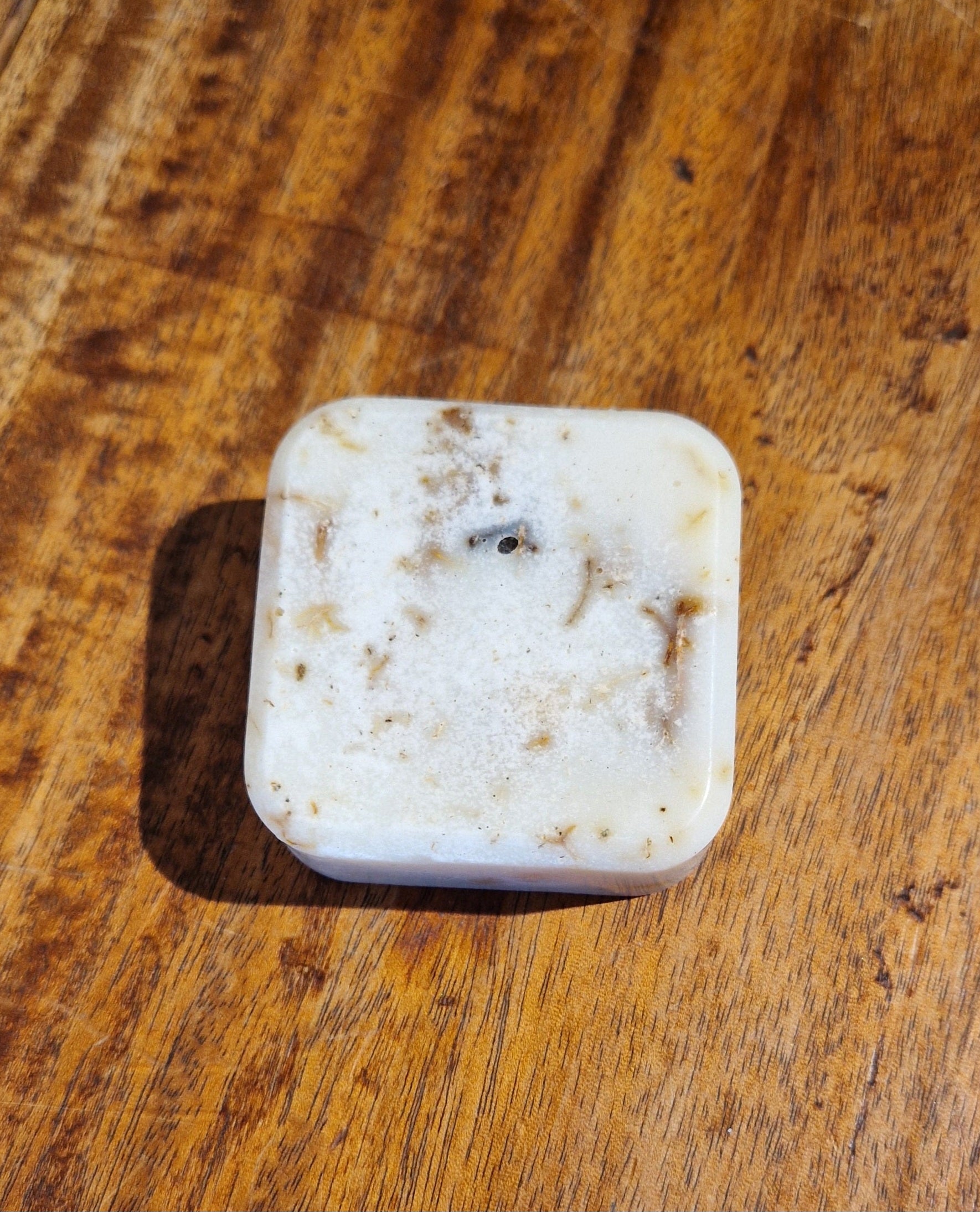 Square piece of white soap on a wooden surface