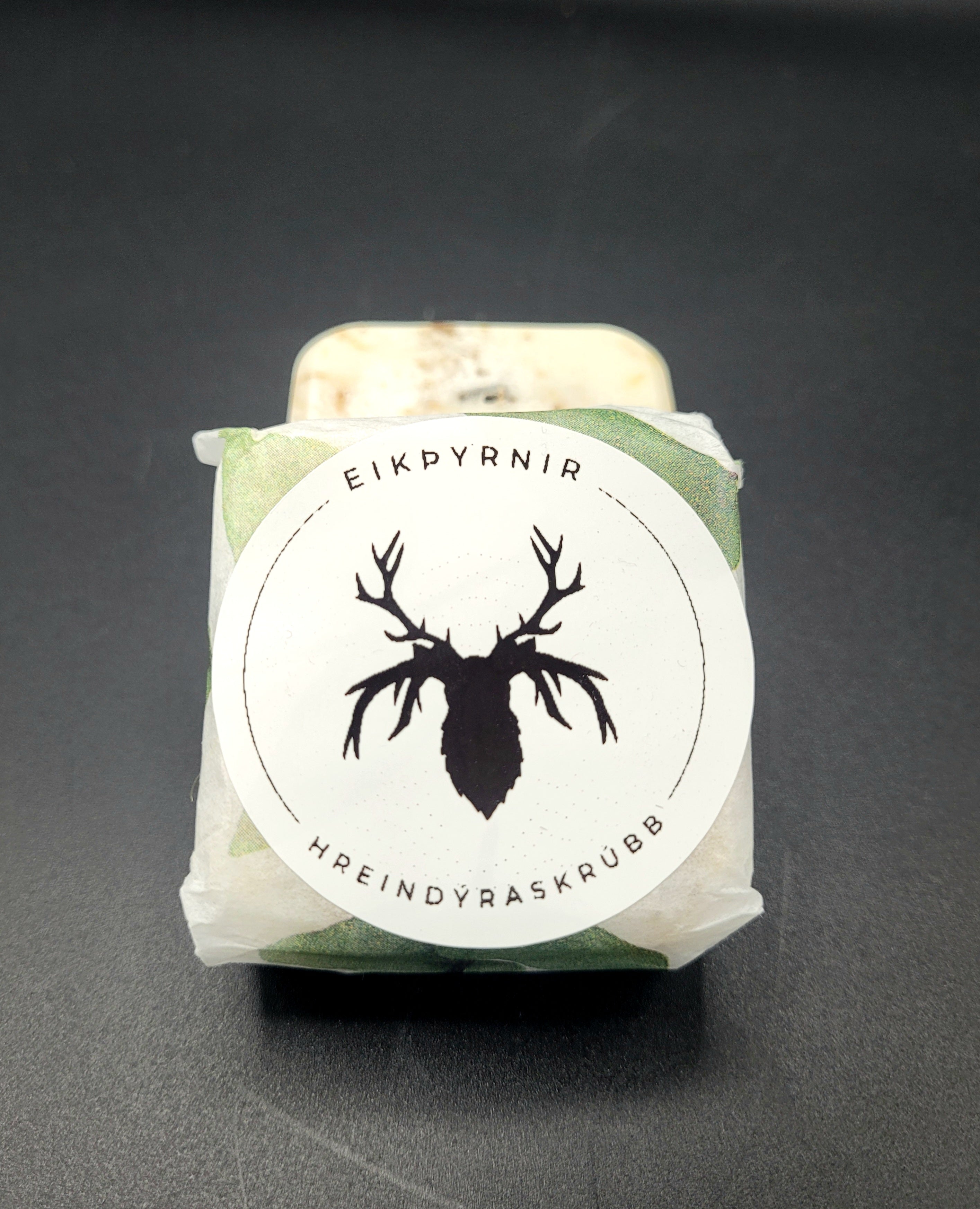 Product wrapped in green paper with a black and white label featuring a deer silhouette on a dark background
