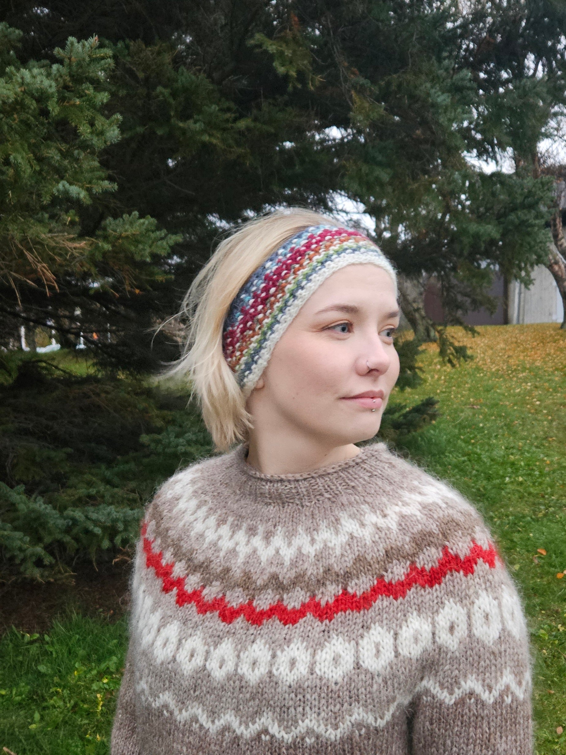 Person wearing a patterned headband and knitted sweater outdoors