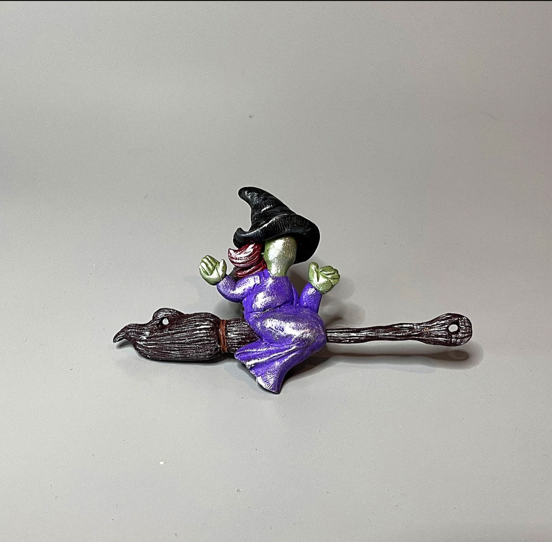 Small figurine of a witch on a broomstick on a plain background