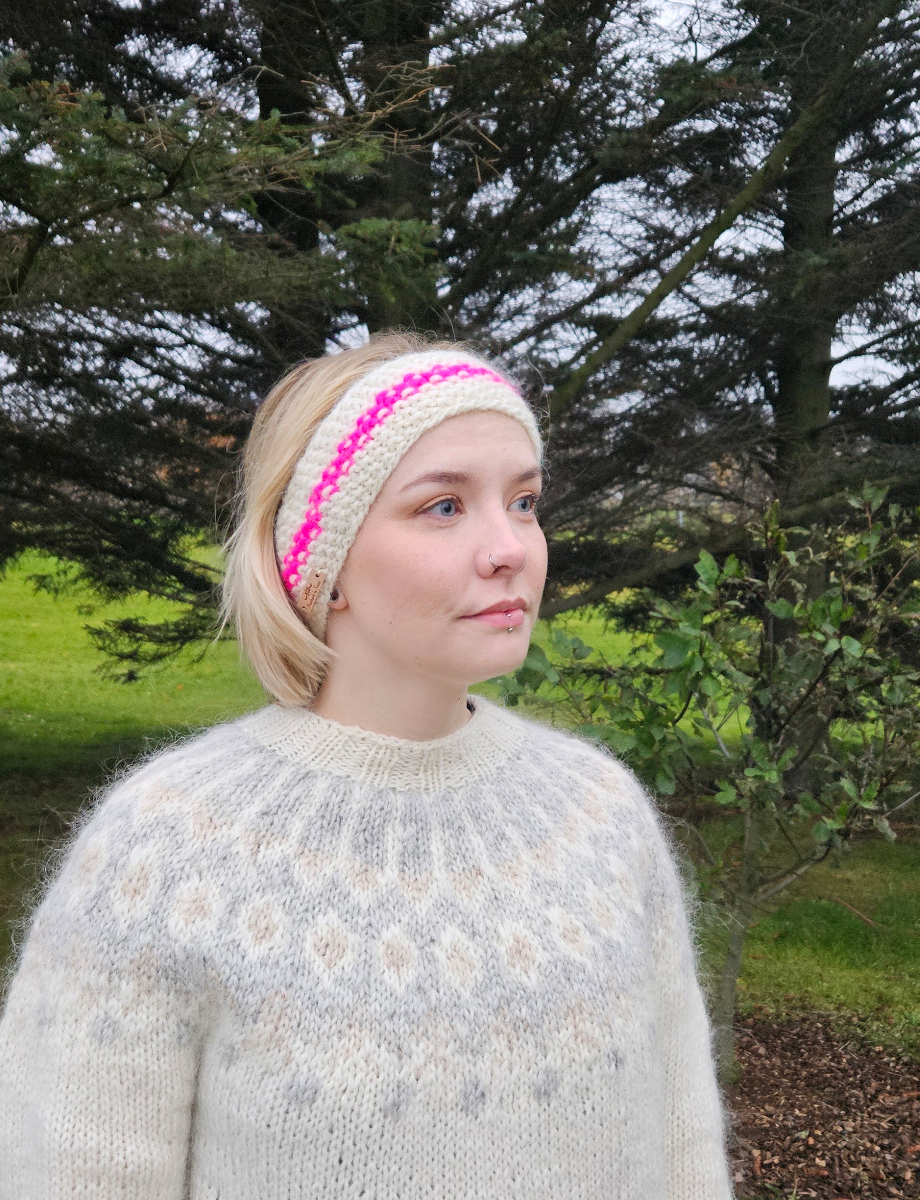 Woman wearing a knitted headband with pink accents outdoors