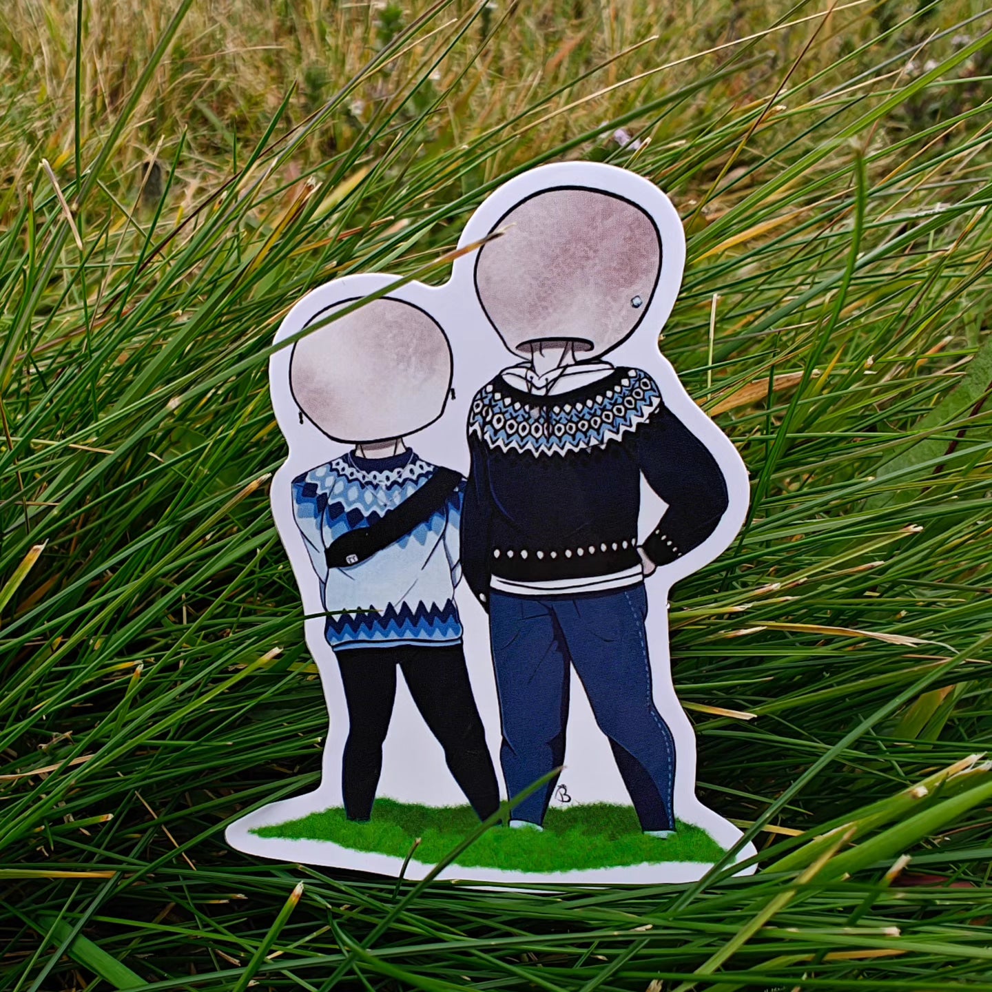 A decorative sticker depicting a cartoonish character in icelandic wool sweaters with a large mushroom head, placed against a backdrop of green grass.