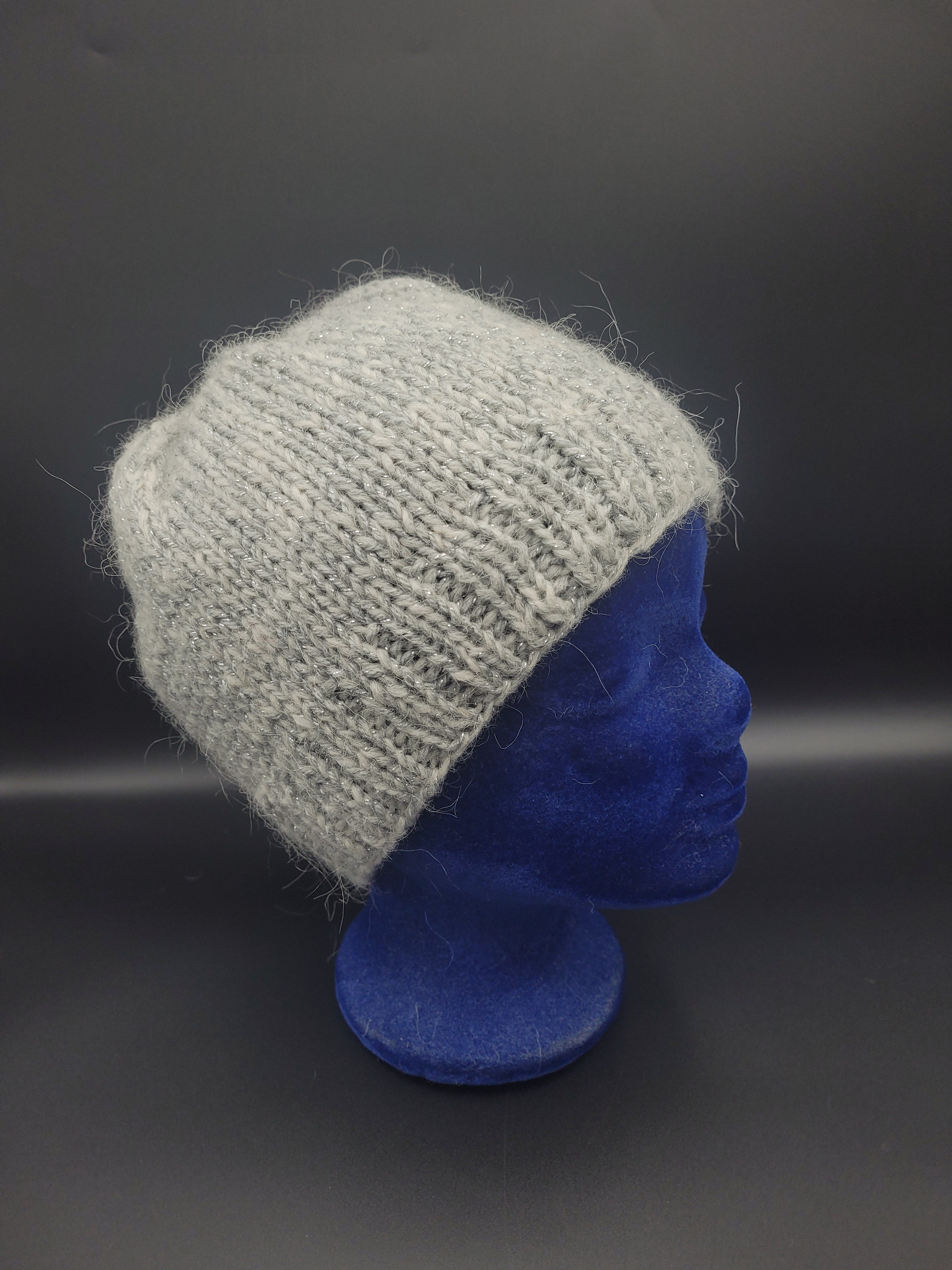 Gray knitted hat on a blue mannequin head against a dark background.