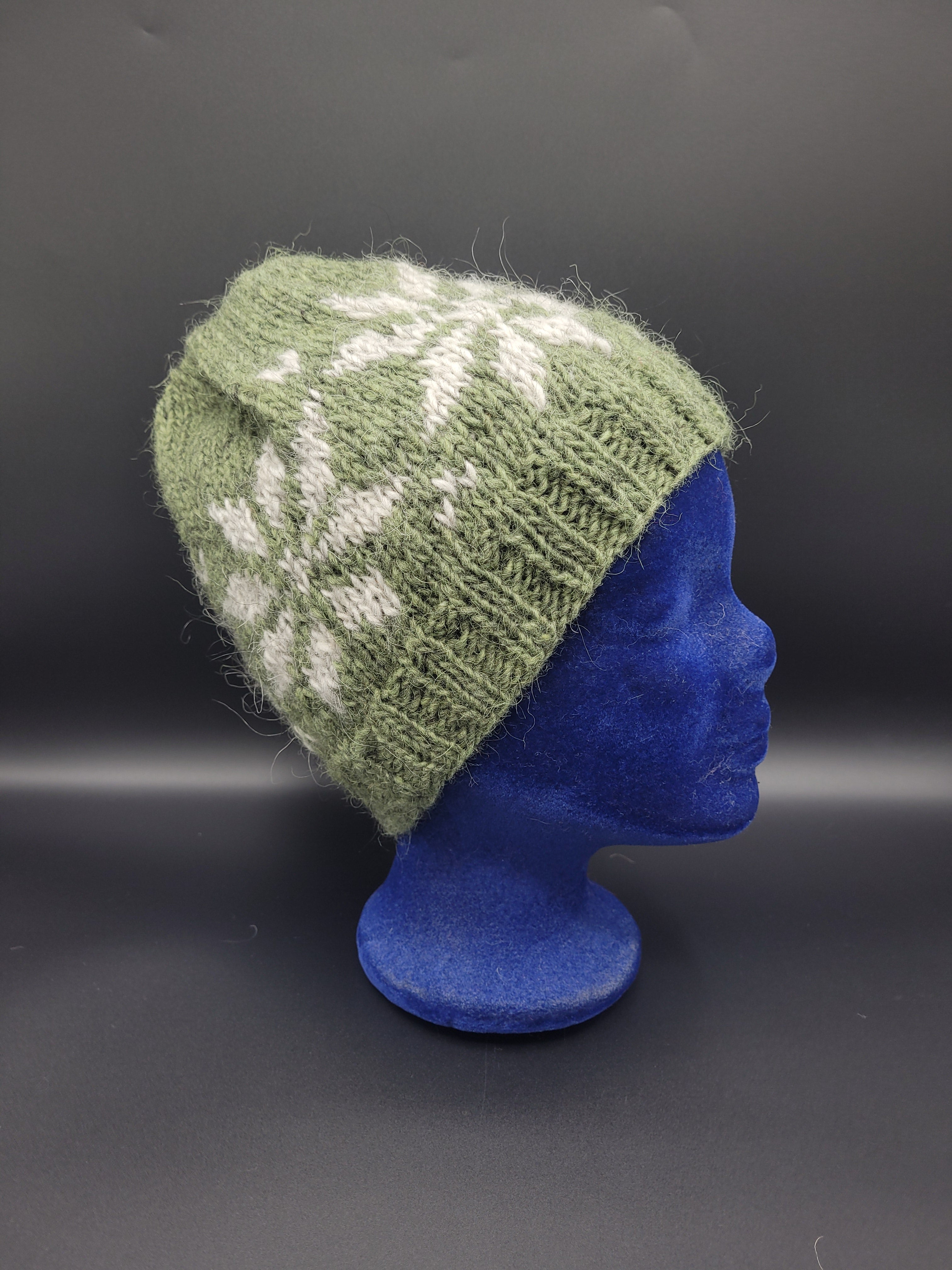 Green knitted hat with white pattern on a black background