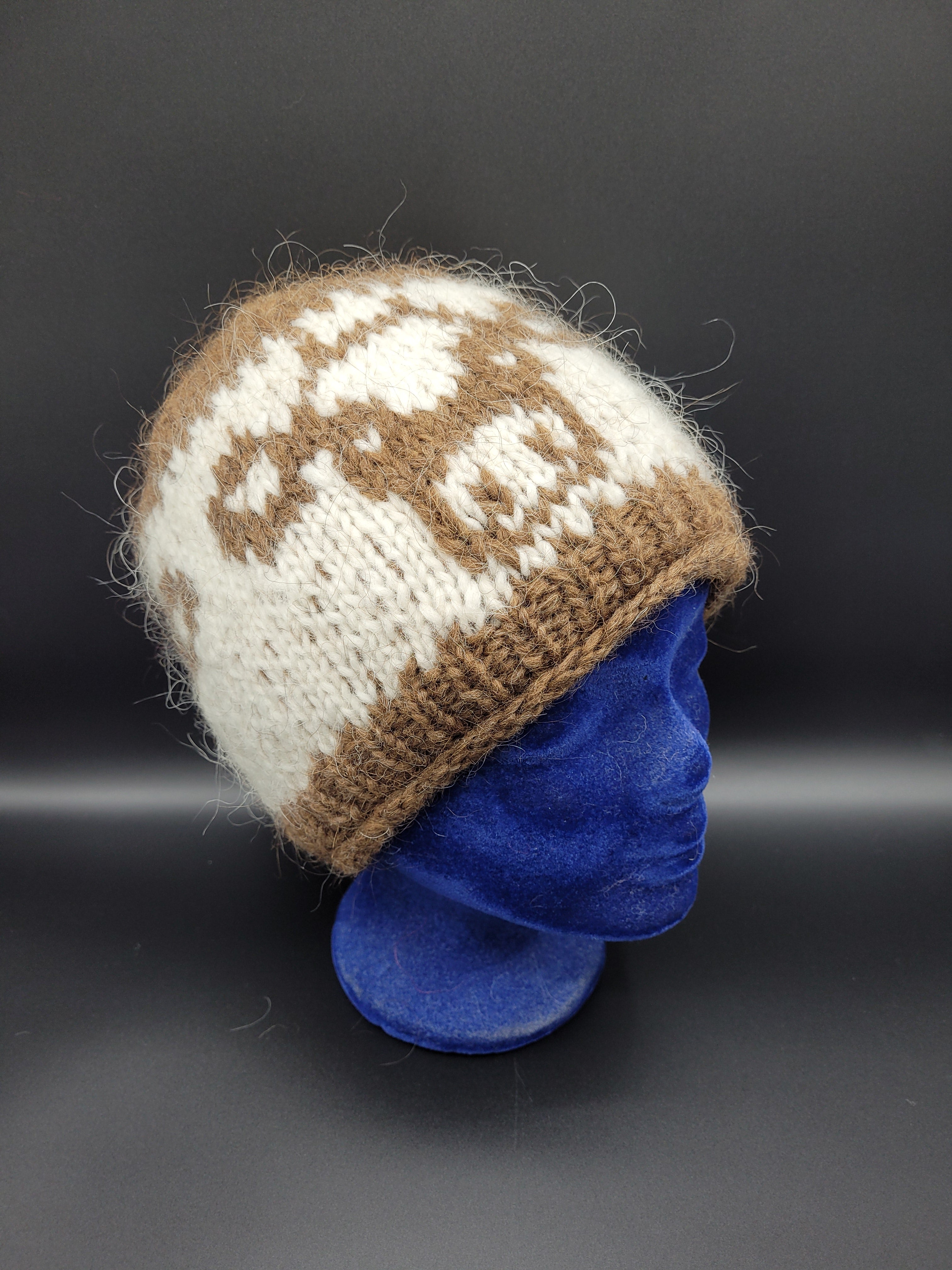 Knitted hat with brown and white pattern and cow pattern on a black background