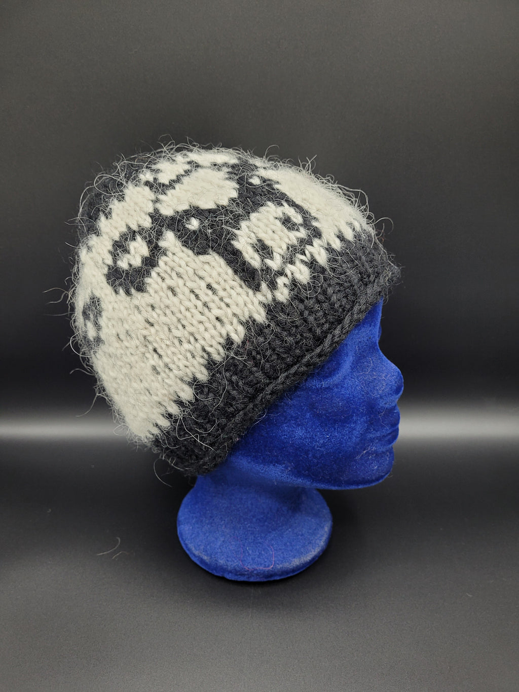 Knitted black and white hat with black cow pattern.